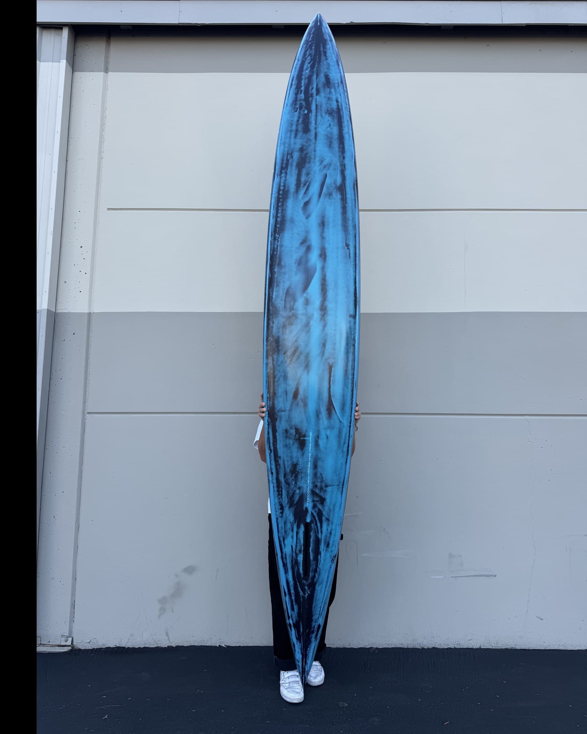 Hull of a custom Lundquist prone paddleboard, showing the displacement bottom and drawn-in tail.