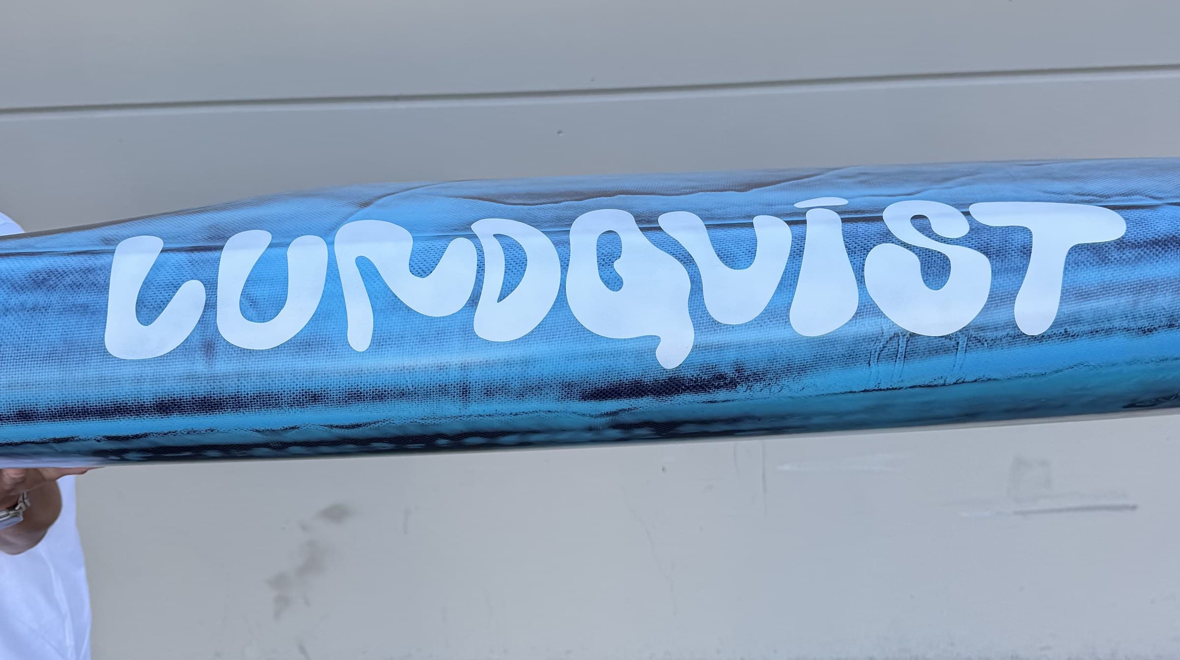 The hand-painted Lundquist logo on the rail of a custom prone paddleboard.